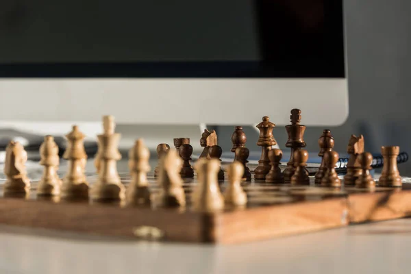 Close-up shot of chess board at workplace near computer — Stock Photo