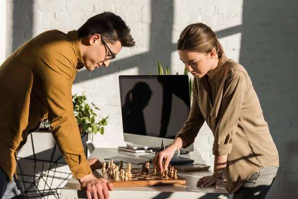 Зосереджені молоді колеги грають в шахи в офісі — стокове фото
