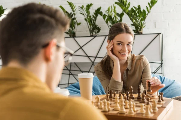 Молодая женщина играет в шахматы и флиртует с противником — стоковое фото