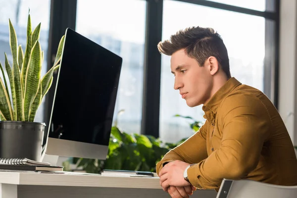 Pensativo joven empresario sentado en el lugar de trabajo - foto de stock