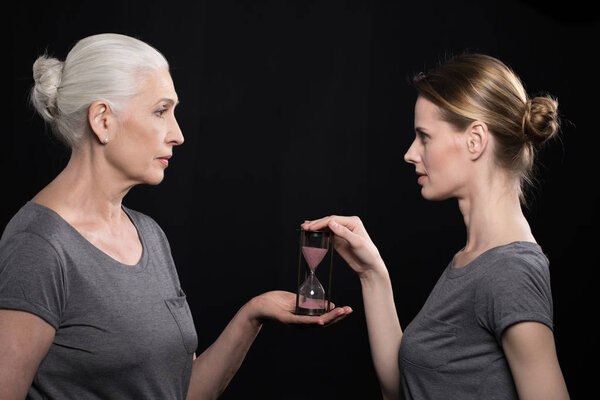 senior woman giving hourglass to daughter