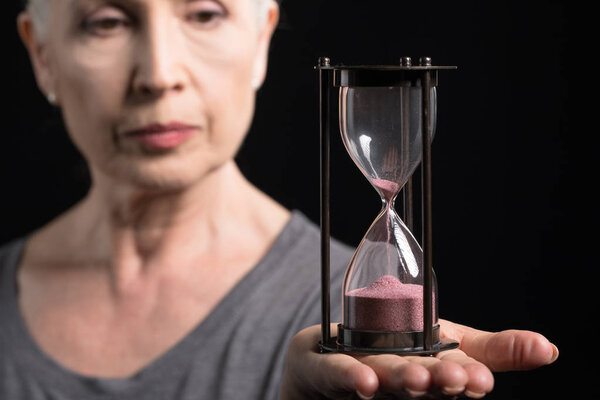 senior woman holding sand clock