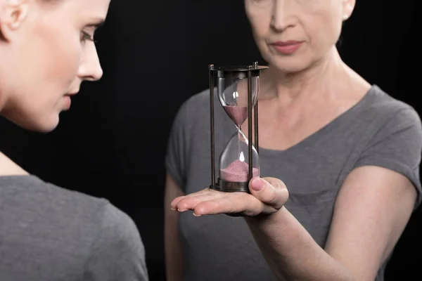 Senior woman giving hourglass to daughter — Stock Photo