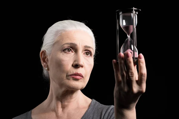 Старшая женщина держит песочные часы — стоковое фото