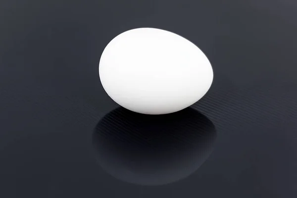 White chicken egg isolated on black glossy background — Stock Photo, Image