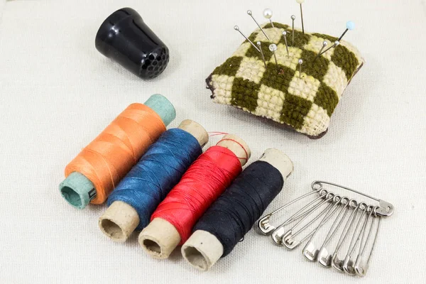 Tejido textil para costura, accesorios para costura sobre nuevo fondo textil. Carrete de hilo, tijeras, dedal, cinta adhesiva, suministros de costura . — Foto de Stock