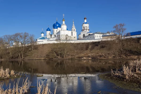 White-stone monastery with sky-blue domes, reflected in the edge of the last winter ice