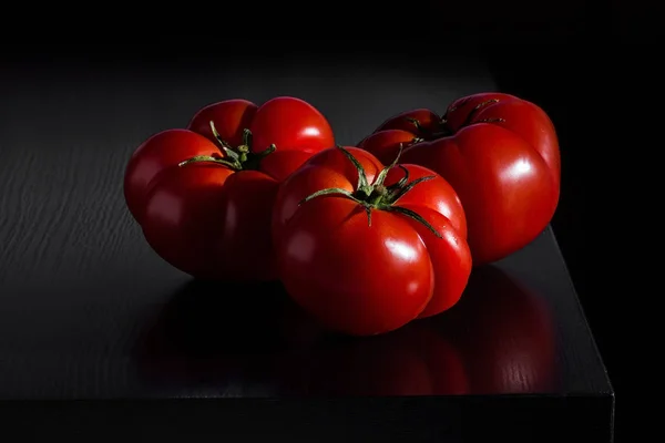Saftige Tomaten auf dunklem Holzgrund — Stockfoto