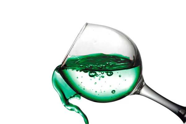 Grönt vatten rinner i ett glas på en vit bakgrund — Stockfoto