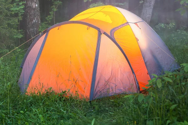 Ljuset brinner i ett tält, en tidig dimmig sommarmorgon — Stockfoto