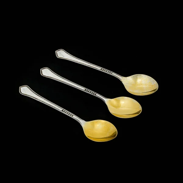 Small silver with gilded spoon on a black background — Stock Photo, Image