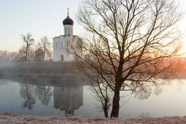 A misty lake with a boat in front of the church in the early spring at dawn Royalty Free Stock Photos