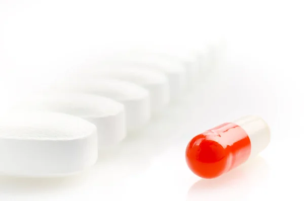 Cápsula roja está en el fondo de las píldoras blancas —  Fotos de Stock