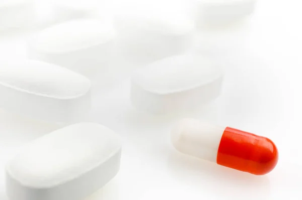 Cápsula roja está en el fondo de las píldoras blancas —  Fotos de Stock