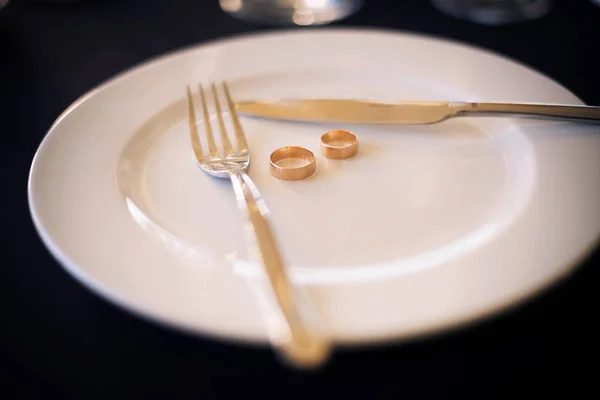 Due anelli di nozze sdraiati su un piatto bianco — Foto Stock