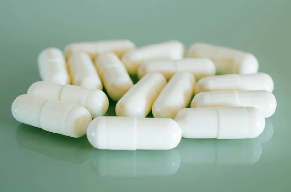 Witte medische capsules liggen op het spiegelend oppervlak — Stockfoto