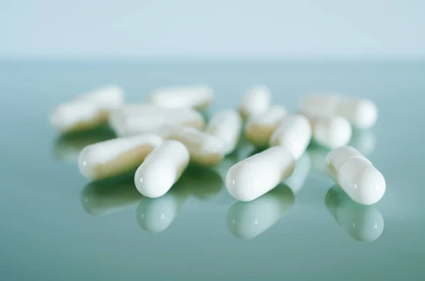 Witte medische capsules liggen op het spiegelend oppervlak — Stockfoto