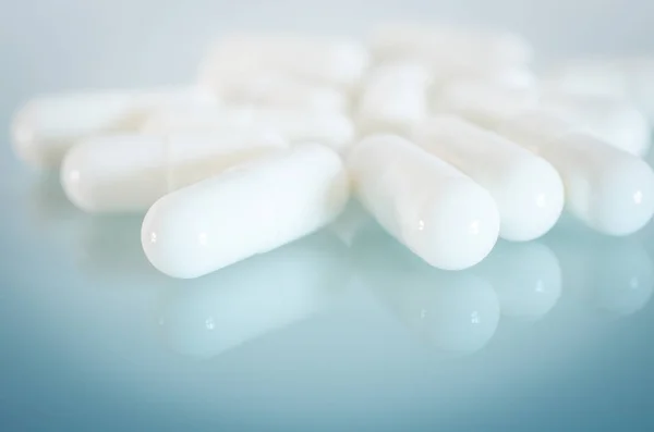 White medical capsules on the mirror surface — Stock Photo, Image