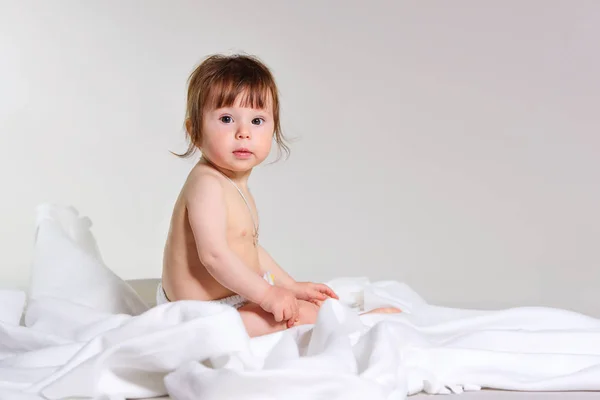 Little girl sitting on a white blanket looking at the camera. place for text — Stock Photo, Image