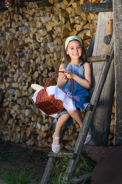 Dítě s úsměvem bez zubů, sedí poblíž dřevěné stěny kůlny — Stock fotografie