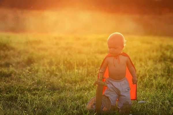 Malý chlapec král venku při západu slunce s paprsek světla — Stock fotografie