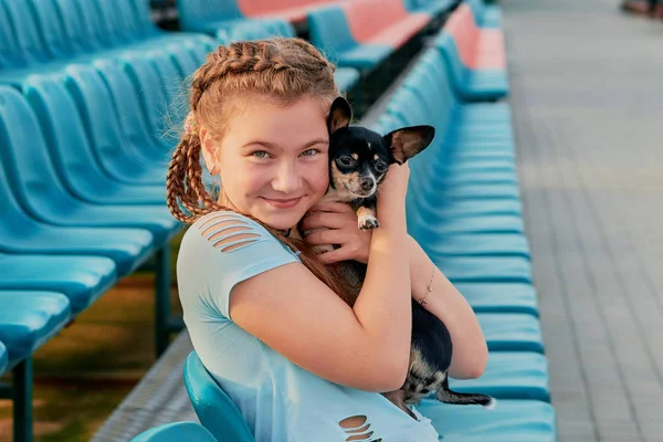 小女孩微笑着轻松与狗。女孩，她的宠物大球场的座位上 — 图库照片