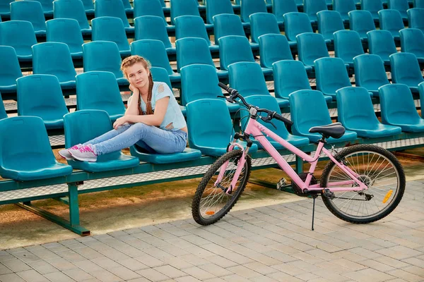 a child posing with the bike.girl child relaxing on the stadium.