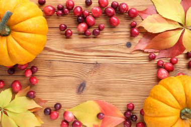 Kare kırmızı kızılcık ve ahşap arka plan üzerinde sonbahar yaprakları ile.