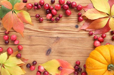 Kare kırmızı kızılcık ve ahşap arka plan üzerinde sonbahar yaprakları ile.