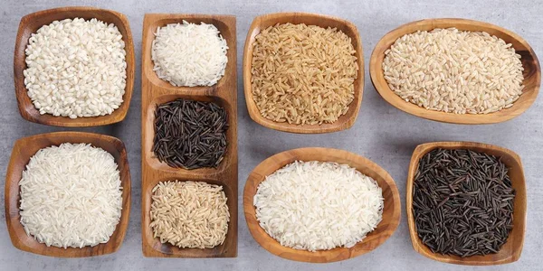 Various types of rice grain in wooden bowls.