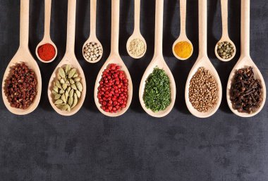 Koyu arkaplanda tahta kaşıklarda Aromatik baharatlar. Üst görünüm.