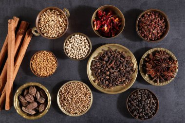 Esmer aromatik baharatlar metal kaselerde koyu bir arka planda. Üst görünüm.