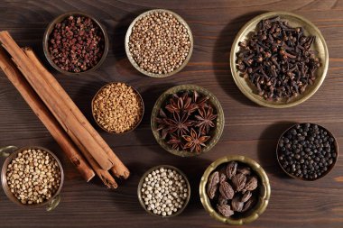 Ahşap arka planda metal kaselerde kahverengi aromatik baharatlar. Üst Manzara. Düz yatıyordu.