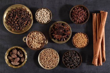 Esmer aromatik baharatlar metal kaselerde koyu bir arka planda. Üst görünüm.