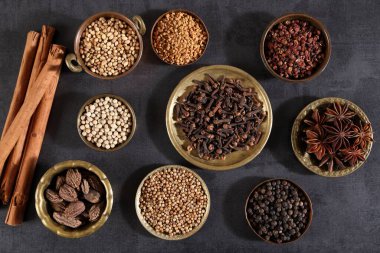 Esmer aromatik baharatlar metal kaselerde koyu bir arka planda. Üst görünüm.