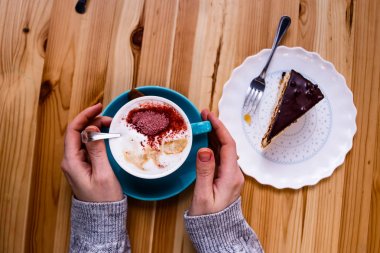 Eller masanın üstüne yalan ve bir fincan kahve pasta yanındaki ahşap bir masa üzerinde tutun