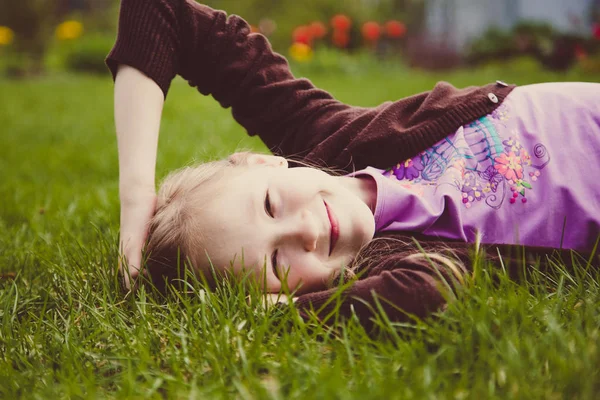 Dívka leží na zelené trávě a smíchu — Stock fotografie
