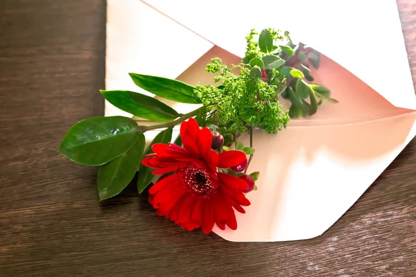 Un ramo de flores de gerberas rojas y una rama verde yacen en un sobre — Foto de Stock