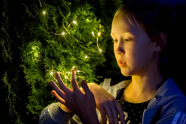 A menina segura as luzes à noite no jardim — Fotografia de Stock