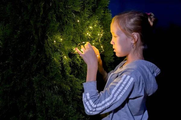 A menina segura as luzes à noite no jardim — Fotografia de Stock