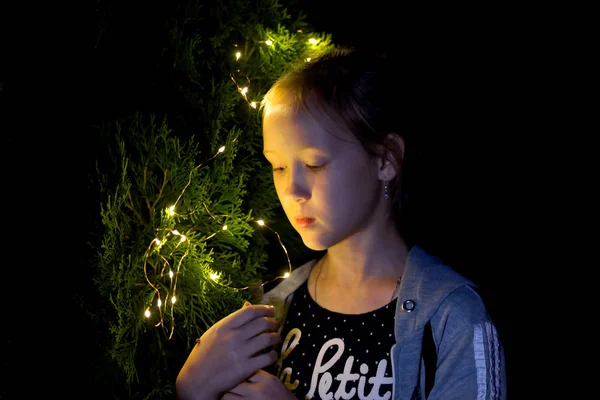 A menina segura as luzes à noite no jardim — Fotografia de Stock