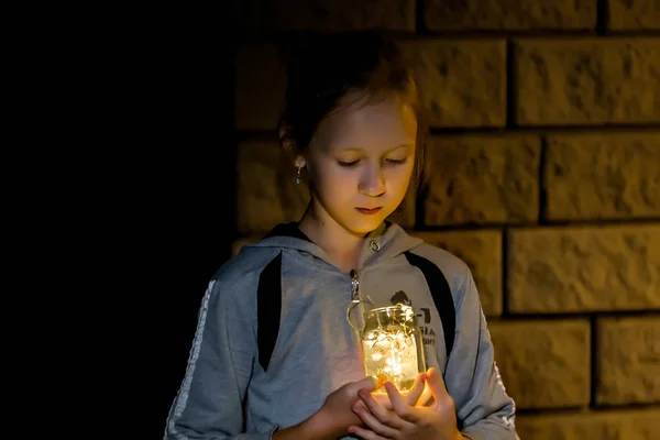 A menina segura as luzes à noite no jardim — Fotografia de Stock