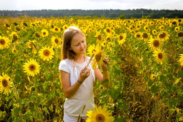 Menina pinta girassóis em um campo — Fotografia de Stock