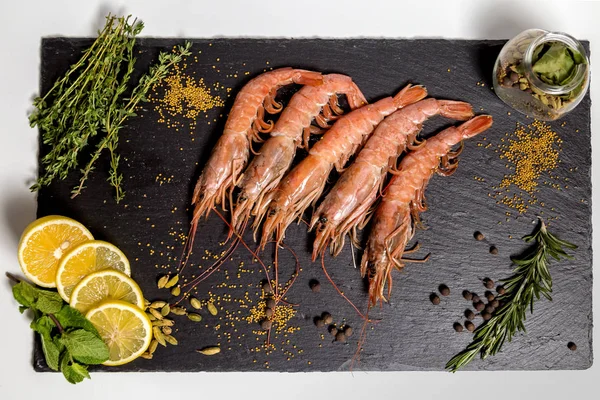 Shrimp langoustine lie on a black plate — Stock Photo, Image