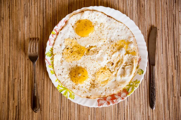Los huevos fritos yacen en un plato sobre una mesa de madera — Foto de Stock