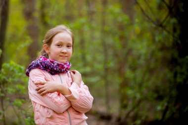 Bir kız pembe ceket güneşin ormanın içinde duruyor