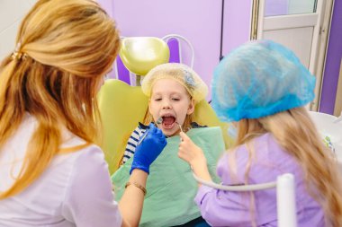 Dişçi çocuklara dişlerini nasıl tedavi edeceklerini öğretir..