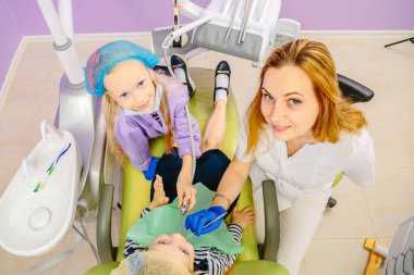 Dişçi çocuklara dişlerini nasıl tedavi edeceklerini öğretir..