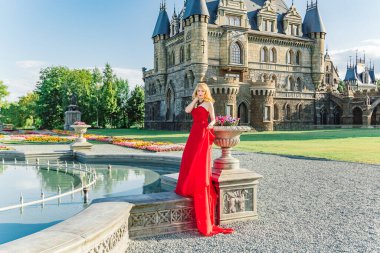 Kırmızı elbiseli bir kadın, Haziran 2019 'da Togliatti' de bir ortaçağ şatosunun arka planında duruyor.