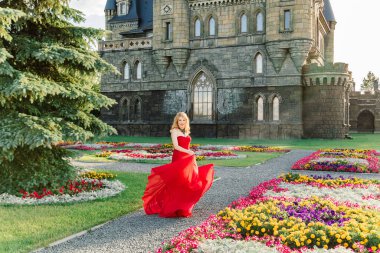 Kırmızı elbiseli bir kadın, Haziran 2019 'da Togliatti' de bir ortaçağ şatosunun arka planında duruyor.